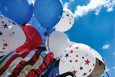 American flag flying with red white and blue party balloons