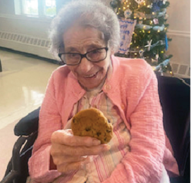 older adult woman holding a chocolate chip cookie in hand